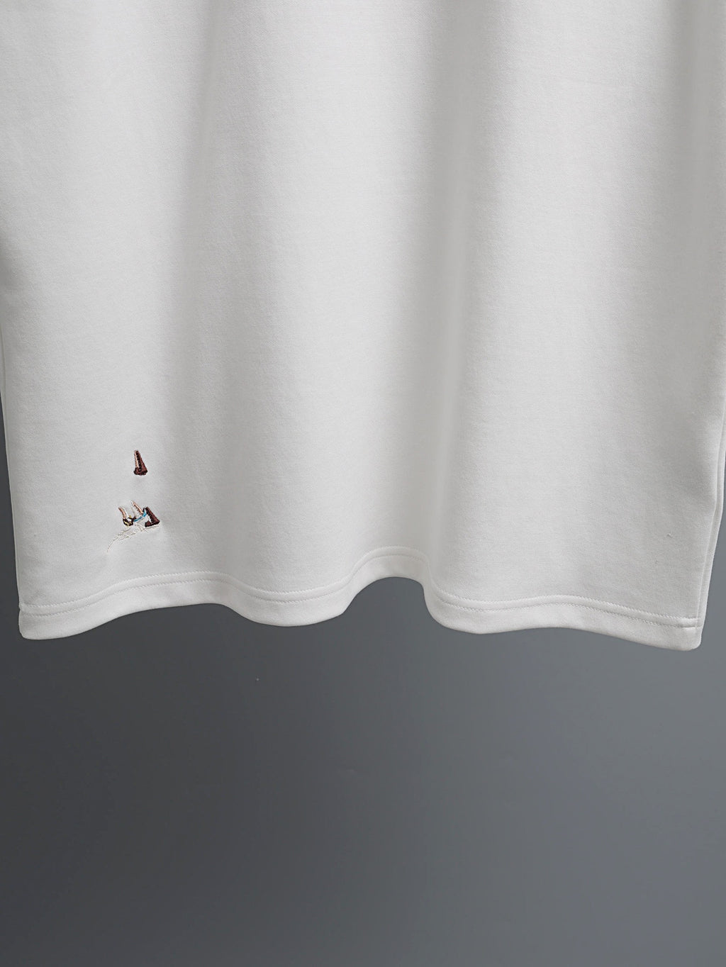 White T-shirt with embroidered bird details along the lower front hem