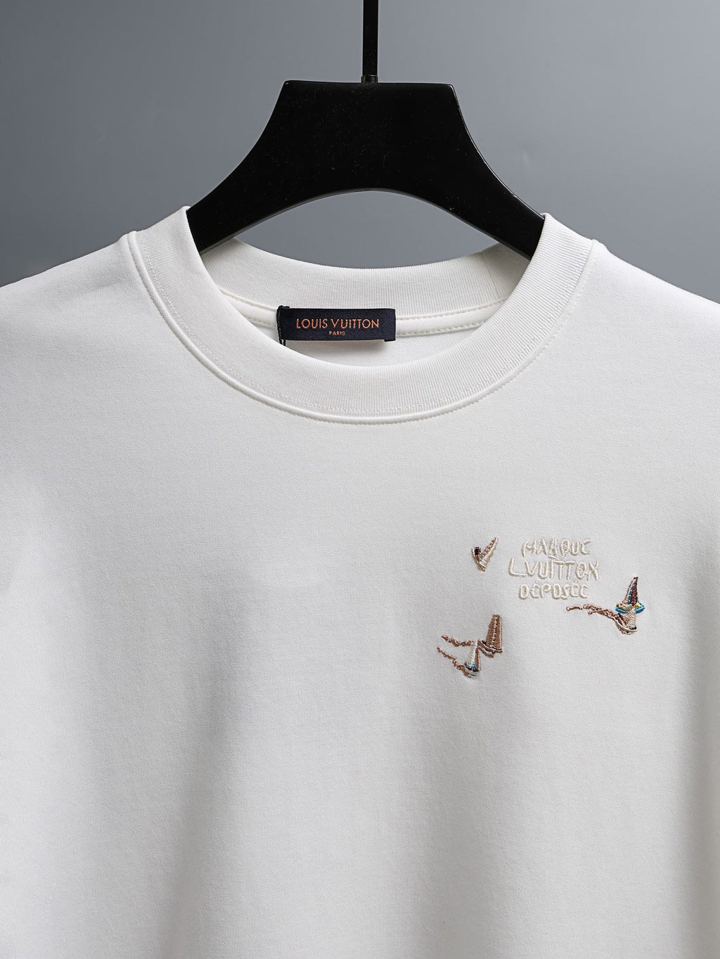 White crewneck T-shirt with neck label and small embroidered bird details at chest