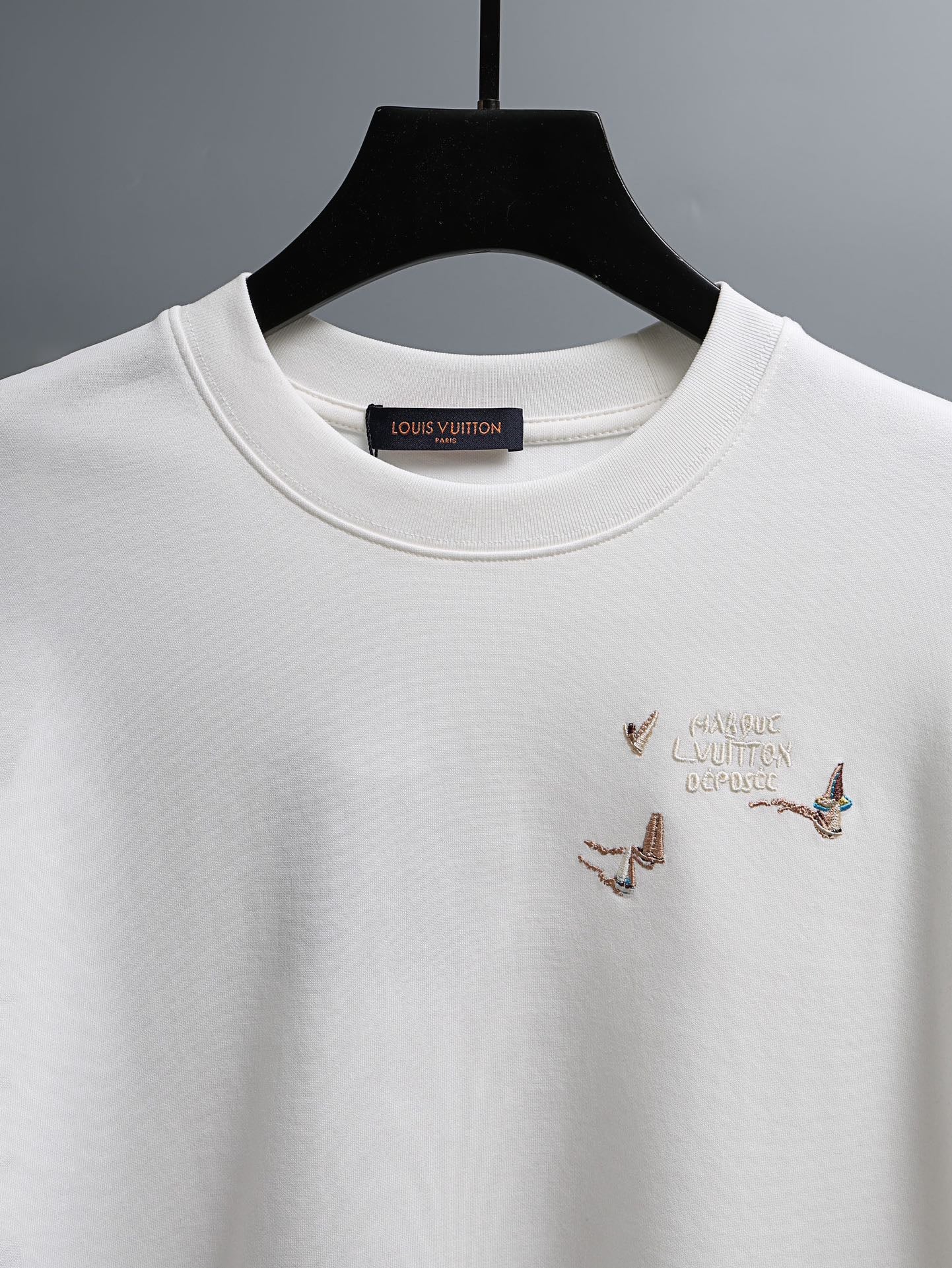 White crewneck T-shirt with neck label and small embroidered bird details at chest