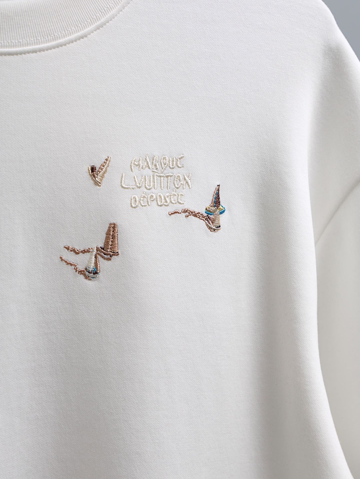 White crewneck T-shirt with multicolor embroidered bird motif at the center chest