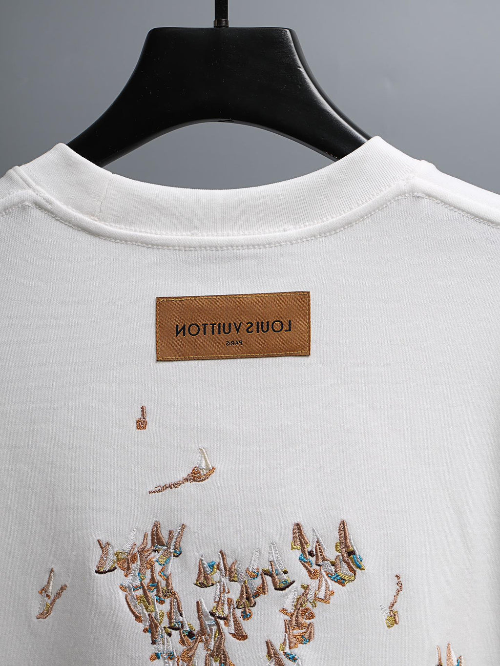 White crewneck T-shirt with brown brand neck label and embroidered bird graphic