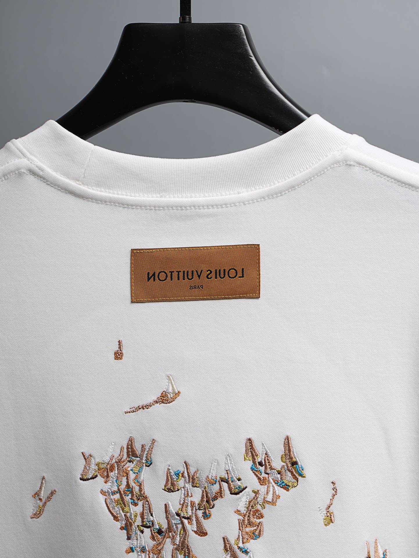 White crewneck T-shirt with brown brand neck label and embroidered bird graphic