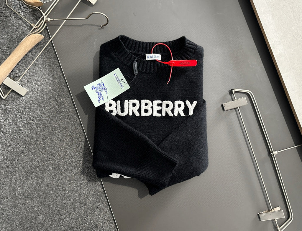 Black knit sweater folded on hangers with BURBERRY logo front