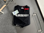 Black knit sweater folded on hangers with BURBERRY logo front