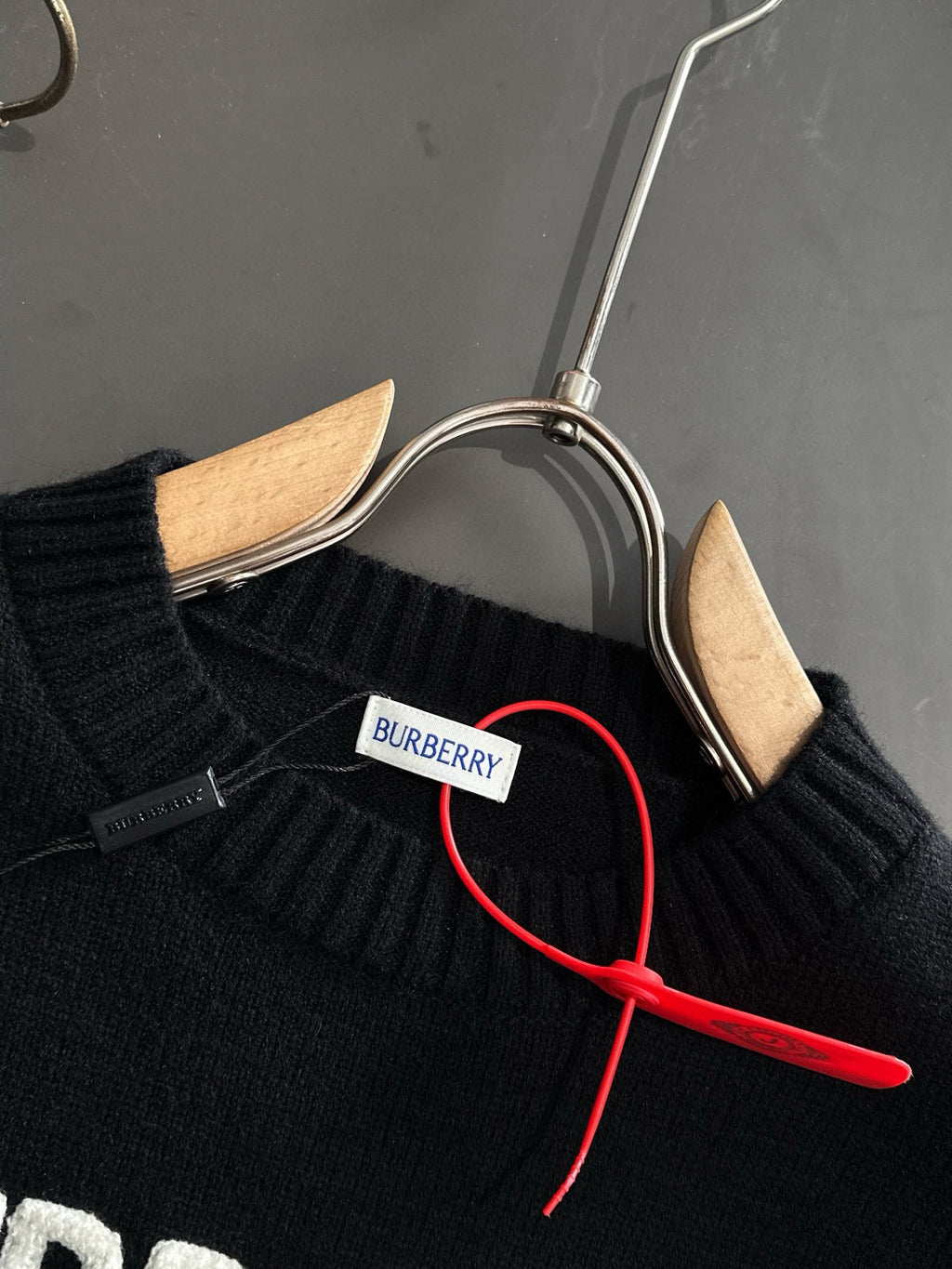 Black knit sweater neckline with BURBERRY neck label and red hanger cord