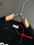 Black knit sweater neckline with BURBERRY neck label and red hanger cord