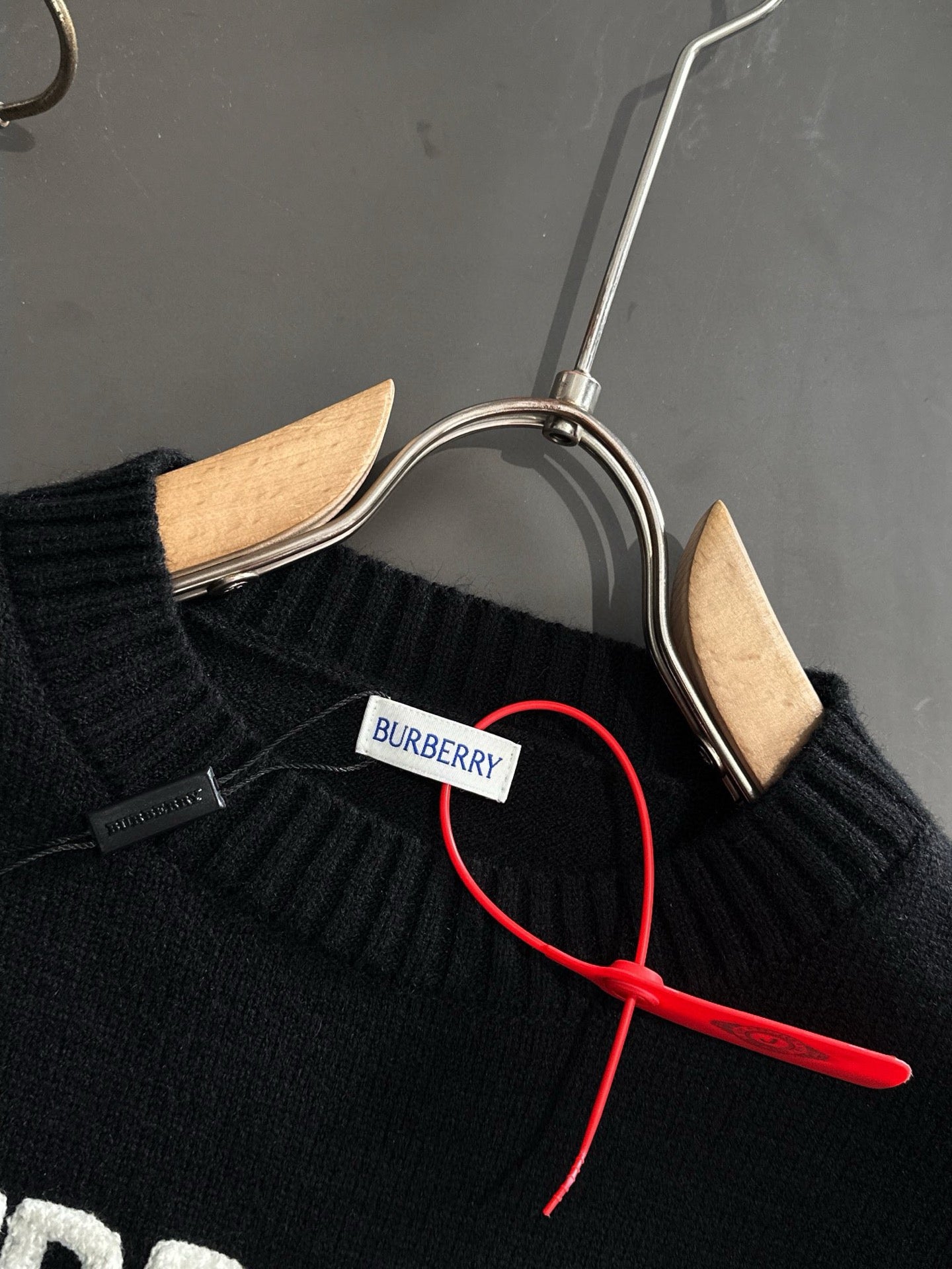 Black knit sweater neckline with BURBERRY neck label and red hanger cord