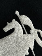 Black knit sweater close-up of white embroidered horse graphic