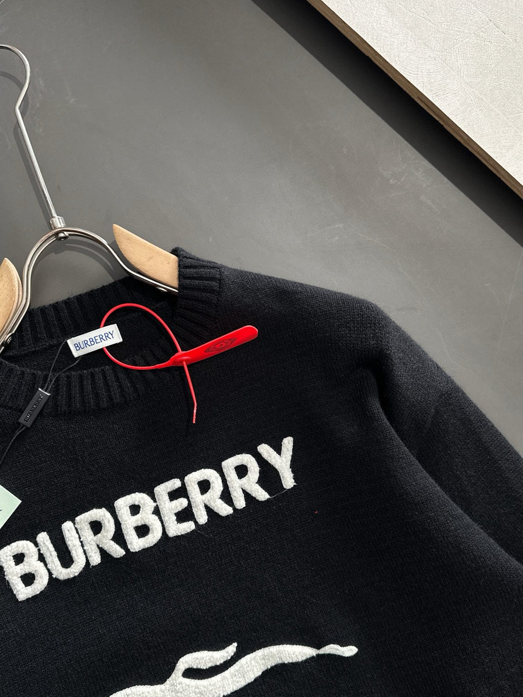 Black knit sweater close-up showing BURBERRY text across chest and zipper trim