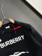 Black knit sweater close-up showing BURBERRY text across chest and zipper trim