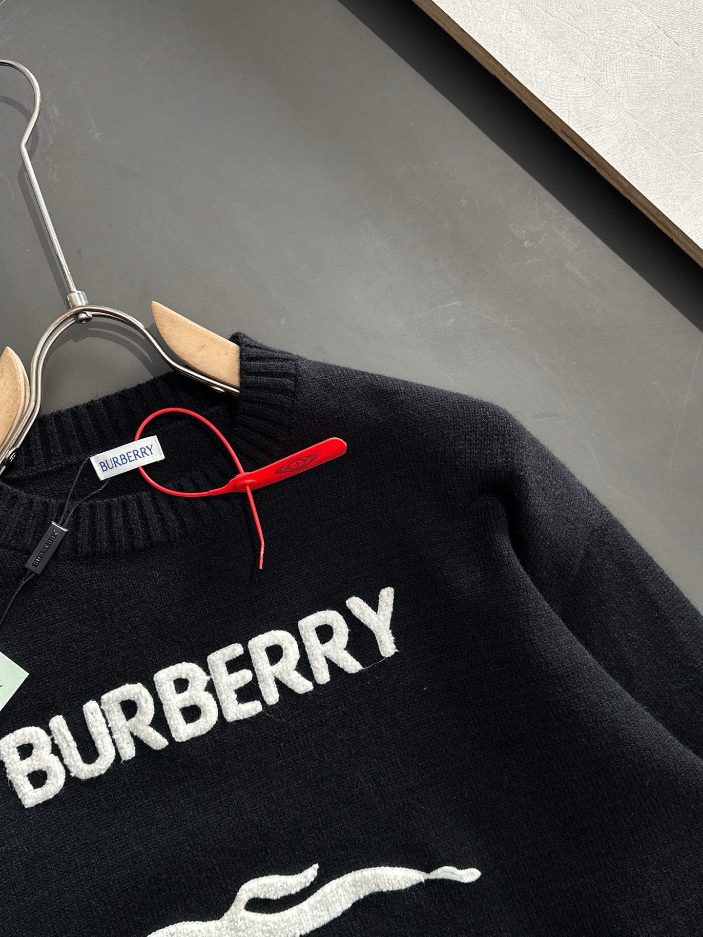 Black knit sweater close-up showing BURBERRY text across chest and zipper trim