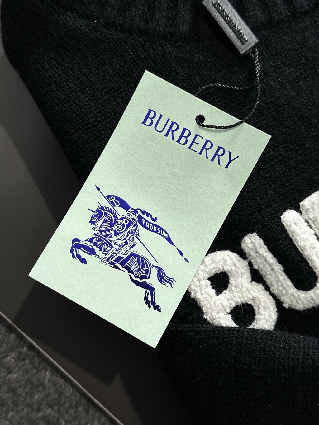 Black knit sweater with green BURBERRY hangtag and blue horse emblem