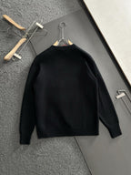 Black knit sweater hanging on wooden hangers, plain front with crew neckline
