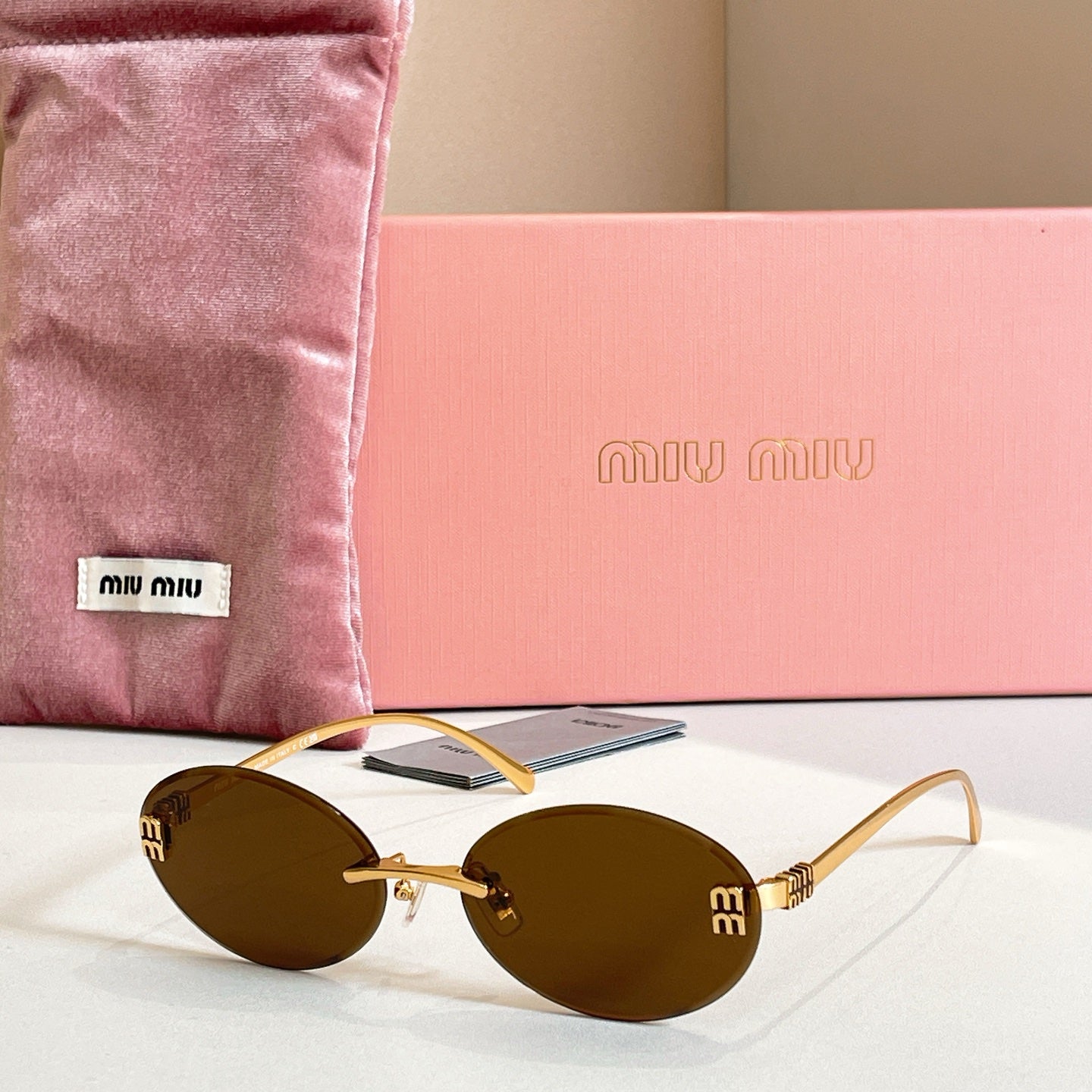 MiuMiu oval sunglasses with gold-tone frame and olive-brown gradient lenses