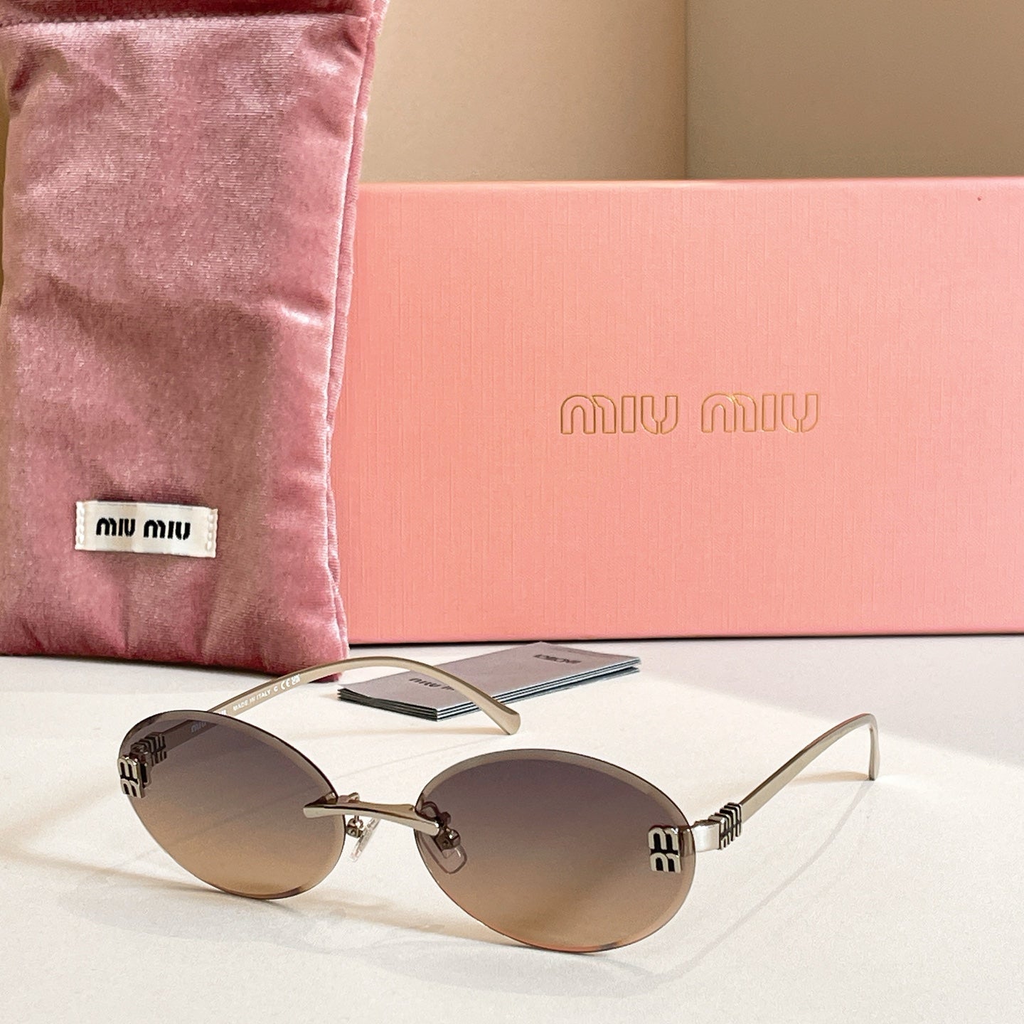 MiuMiu oval sunglasses with gold-tone frame and smoky gray gradient lenses