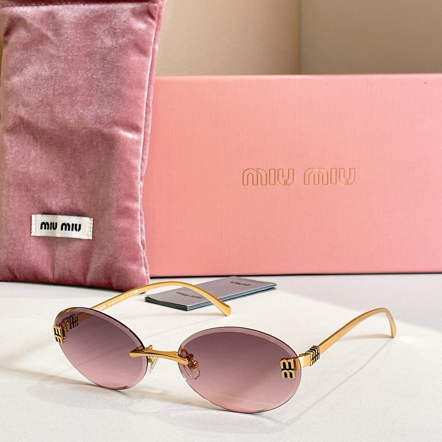 MiuMiu oval sunglasses with gold-tone frame and purple-pink gradient lenses