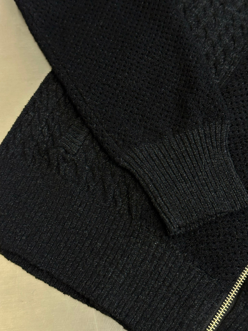Dark knit sweater cuff and ribbed hem with gold zipper