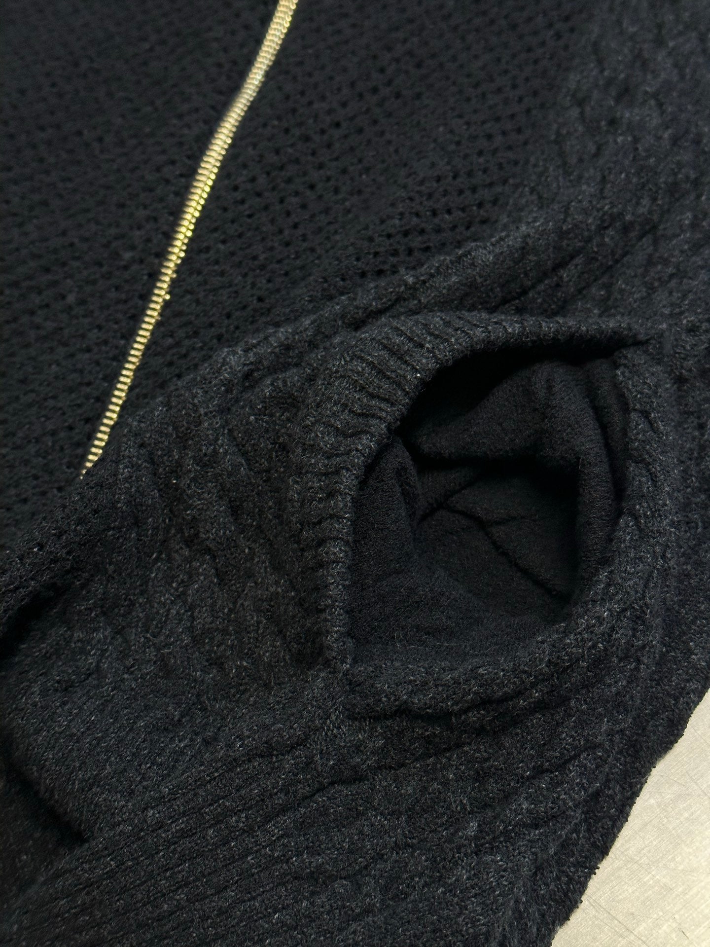 Dark knit sweater close-up of collar opening and gold zipper