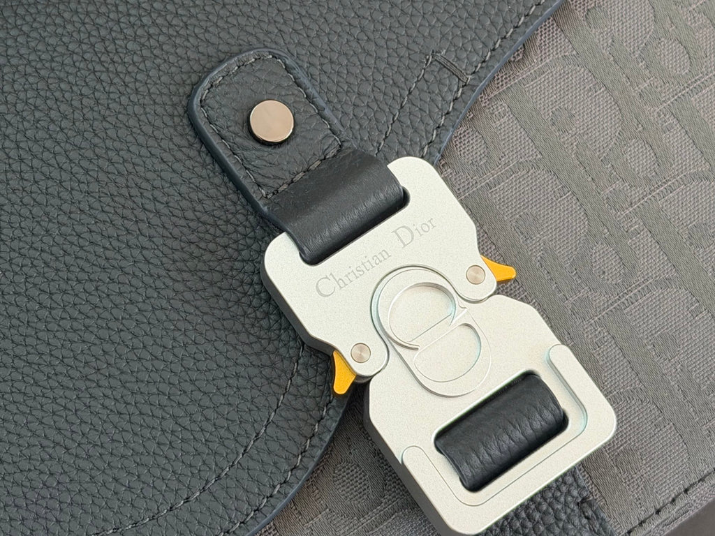 Dior bag clasp detail with engraved metal plate, yellow accent, and leather tab