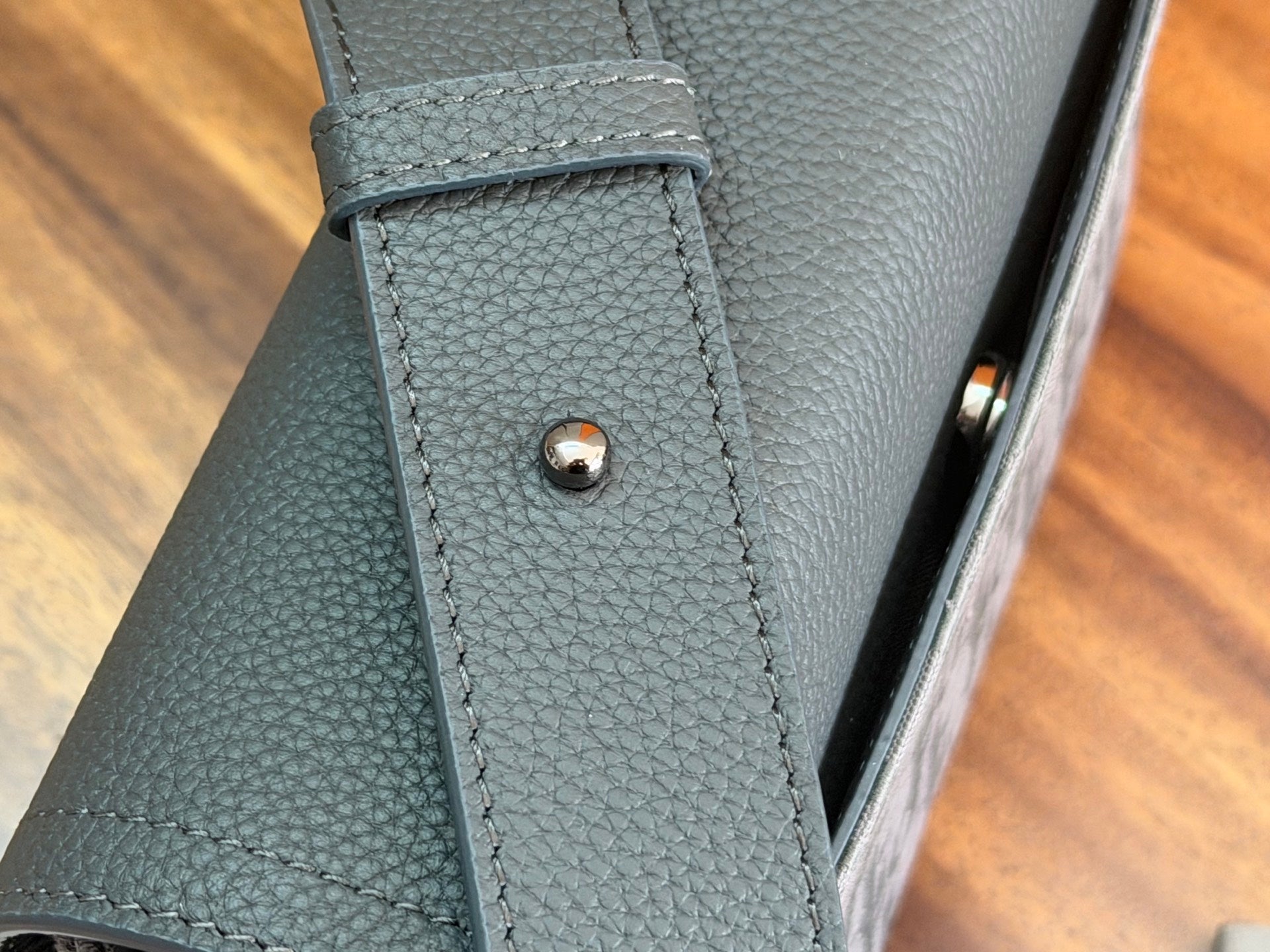 Dior bag corner close-up with stitched leather panel and metal snap stud
