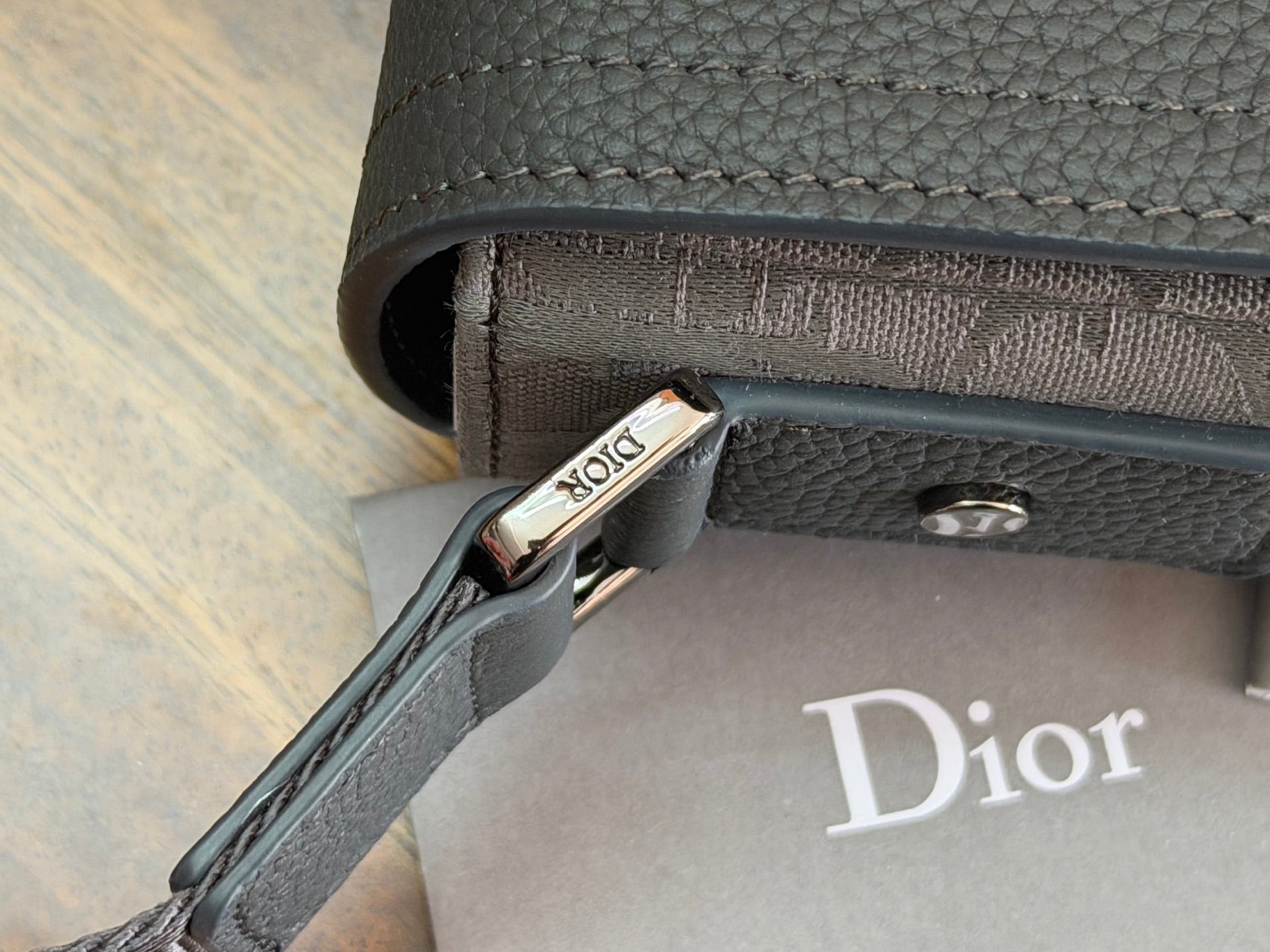 Dior bag side hardware and stitched strap end with metal clasp at the edge