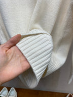 Cream ribbed knit sleeve cuff held by hand, showing tight knit texture