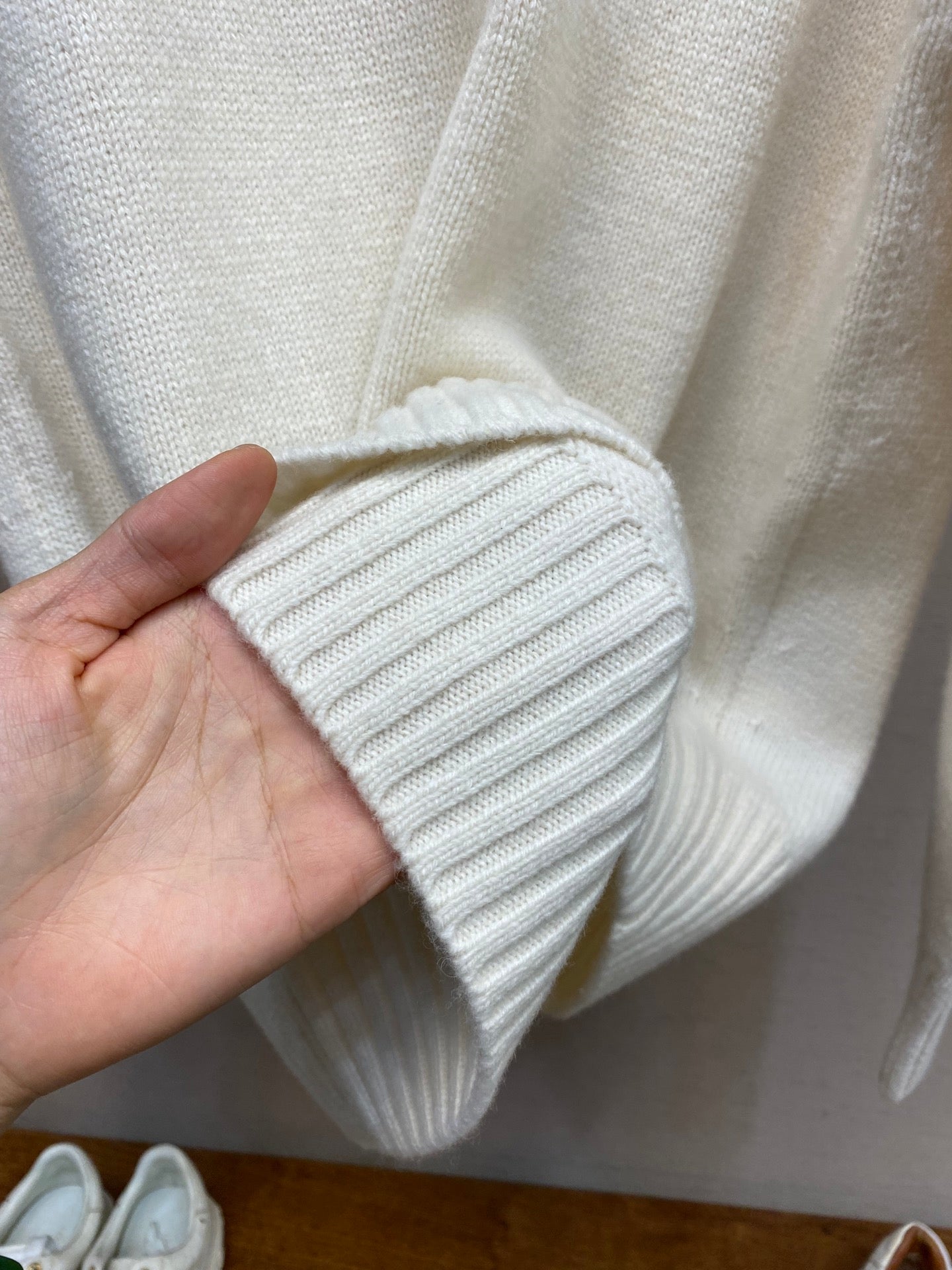 Cream ribbed knit sleeve cuff held by hand, showing tight knit texture