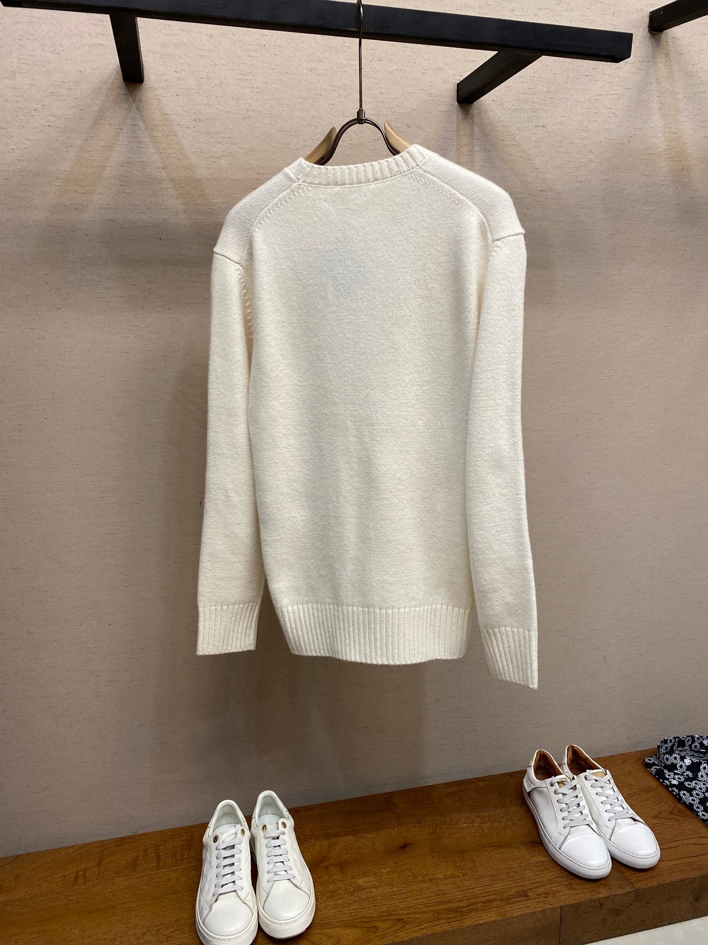 Cream long-sleeve knit sweater on hanger, crew neckline and ribbed hem and cuffs