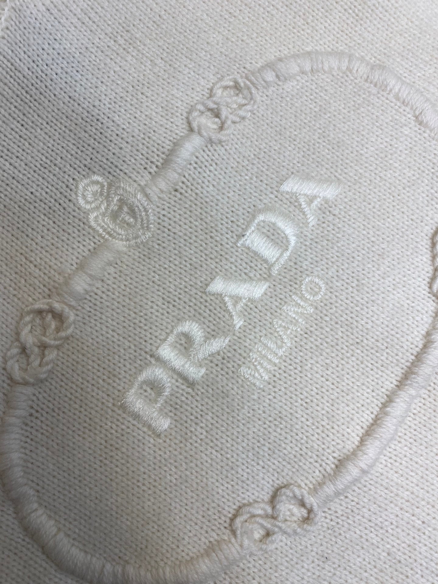 Cream knit texture with PRADA chain and logo embroidery detail