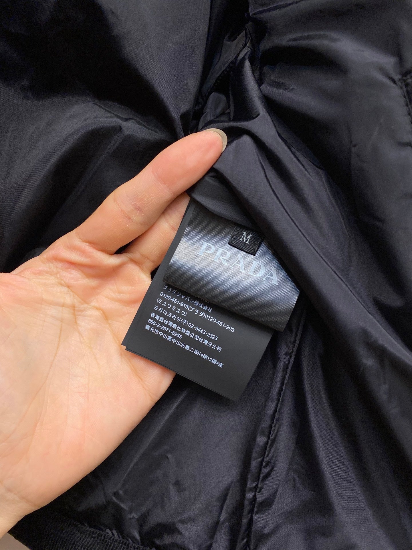 Black satin fabric tag reading PRADA with product info label