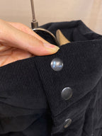 Close-up of black puffer jacket snap buttons on dark fabric