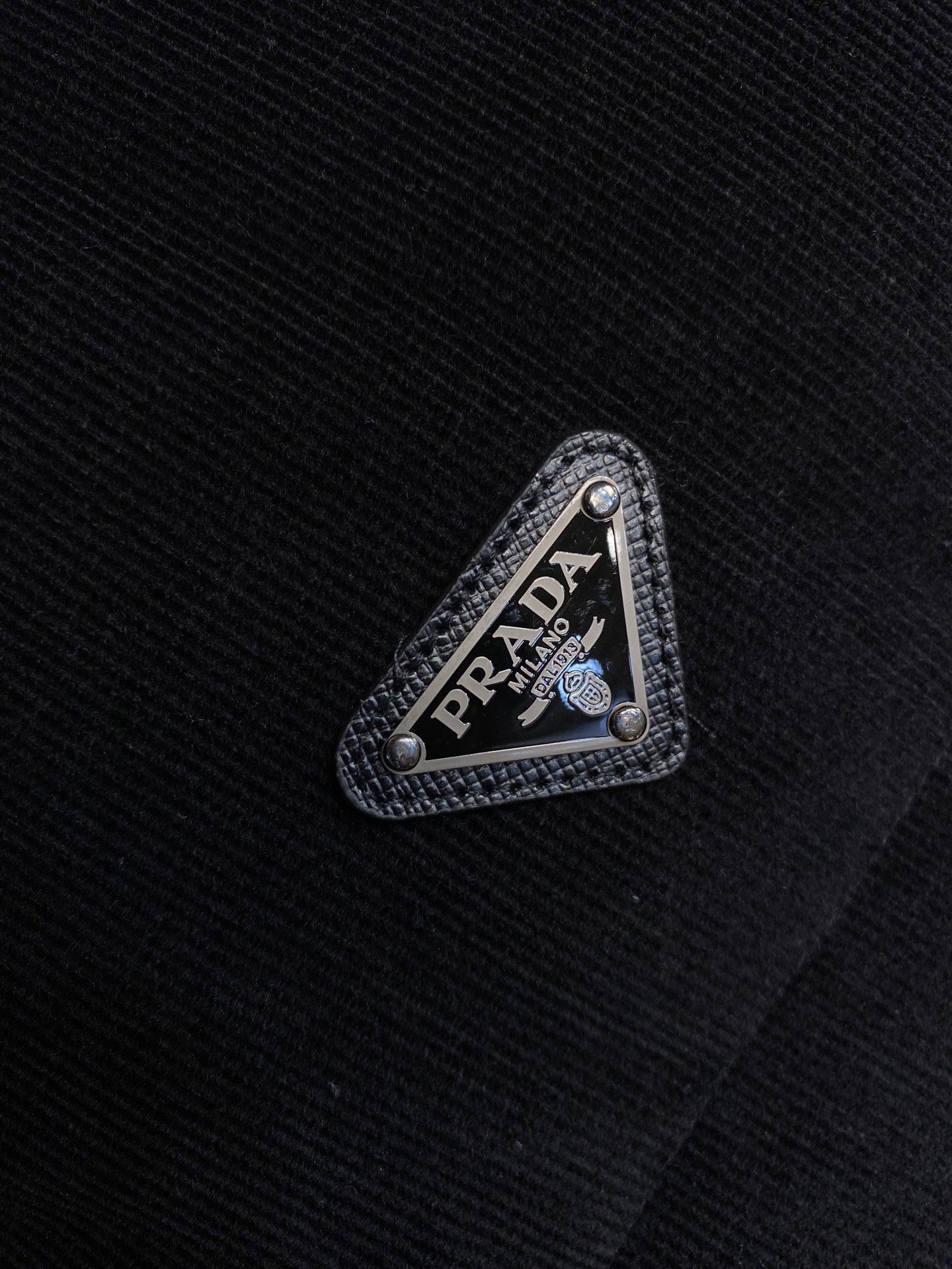 Prada triangle logo patch on black fabric