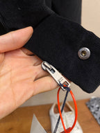 Black cuff with snap button and Prada-branded zipper pull