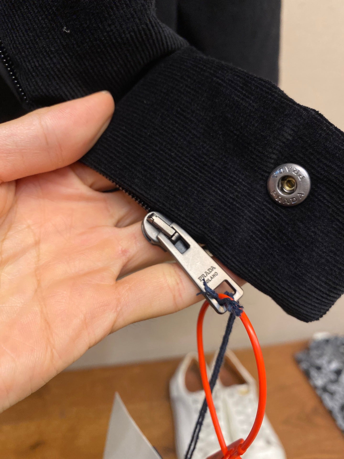 Black cuff with snap button and Prada-branded zipper pull