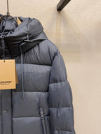 Side view of dark gray long puffer jacket with hood and zipper