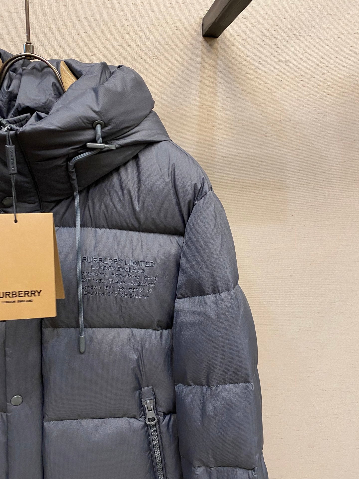 Side view of dark gray long puffer jacket with hood and zipper