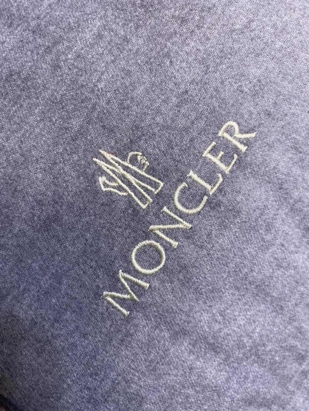 Moncler logo embroidery on light gray puffer jacket fabric