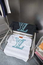 Set of two Louis Vuitton logo T-shirts on display: navy and white with turquoise print