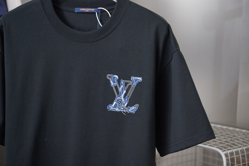 Close-up of dark short-sleeve T-shirt with small blue embroidered LV monogram on chest