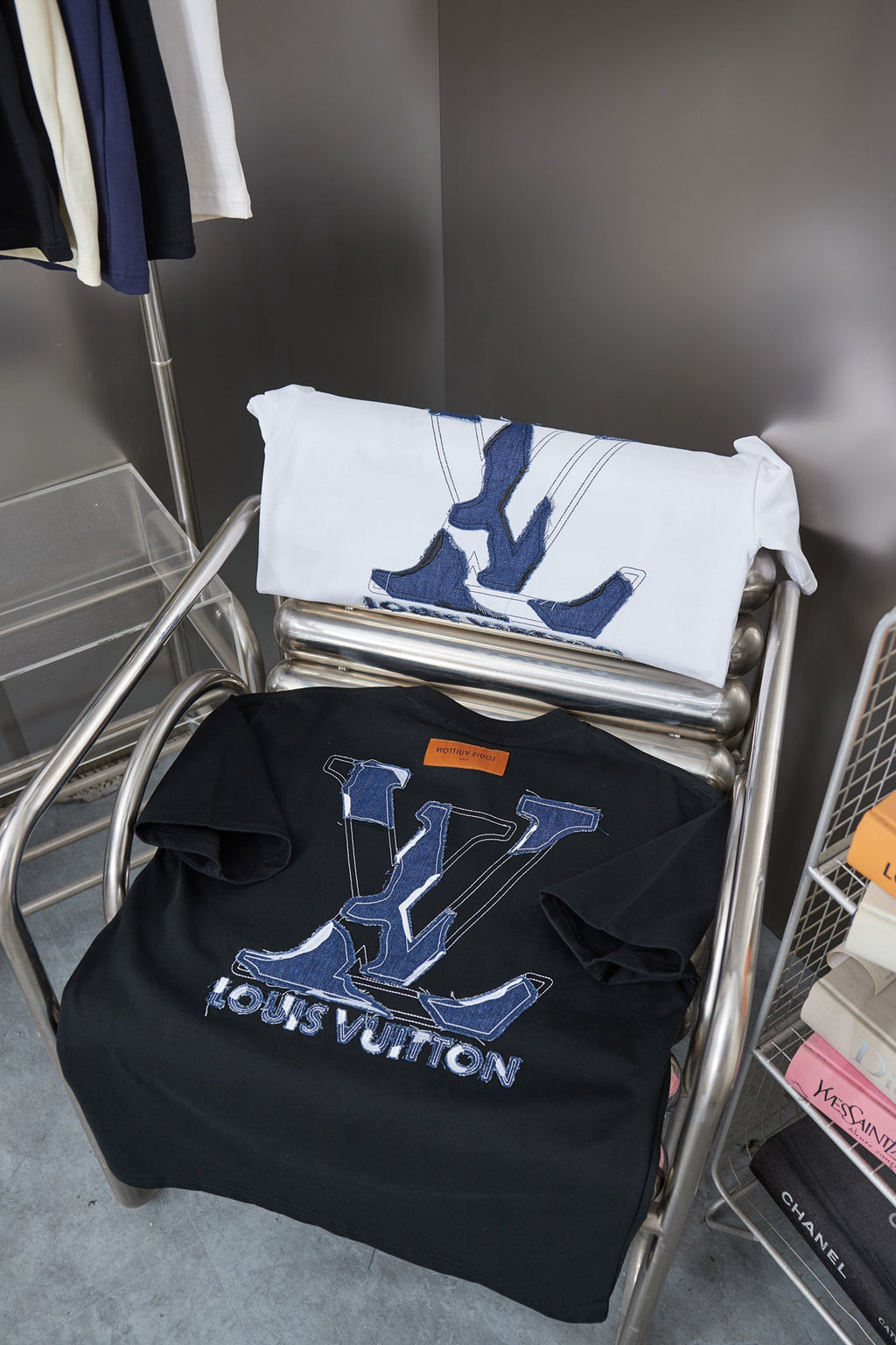 T-shirt rack with folded white and dark shirts featuring blue LV monogram prints