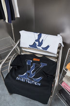 T-shirt rack with folded white and dark shirts featuring blue LV monogram prints