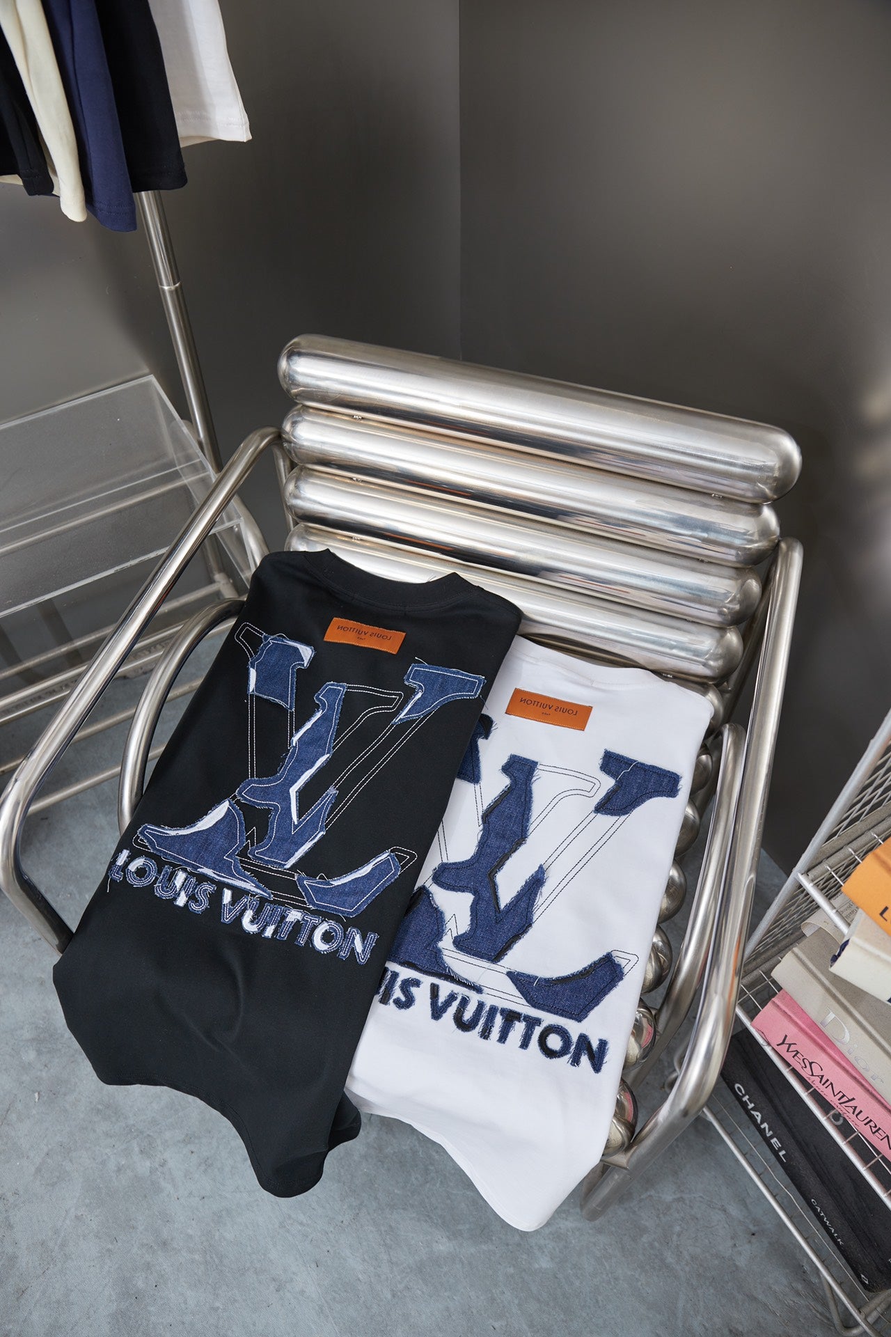 Two folded T-shirts on rack: dark and white styles with blue LV monogram prints