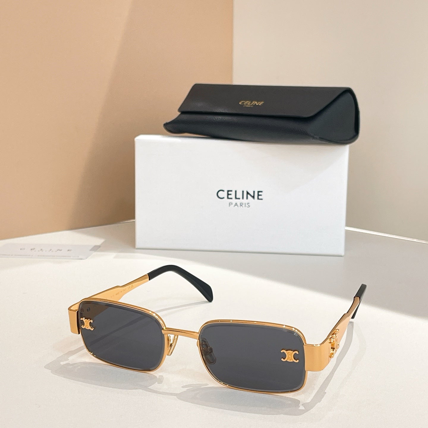 Dark square sunglasses with black frames and gold-tone emblem accents