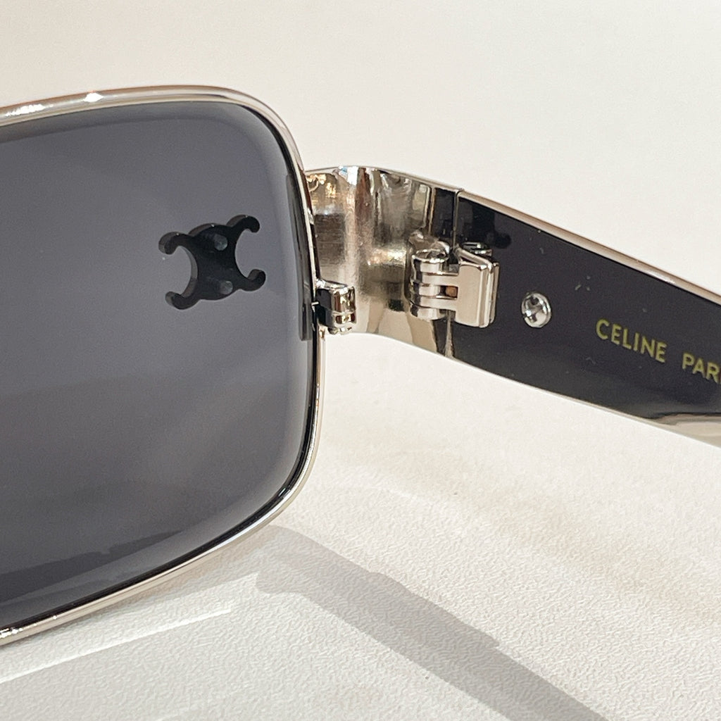 Close-up of dark lens sunglasses with metal hinge and brand logo on temple