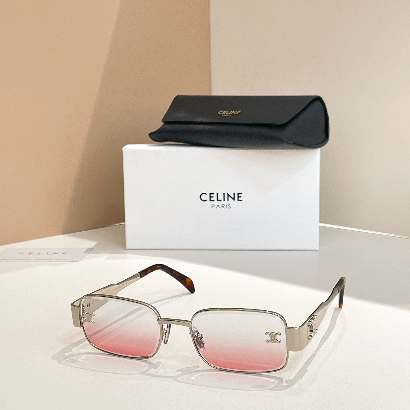 Rose-tinted square sunglasses with gold-tone frames and clear arms