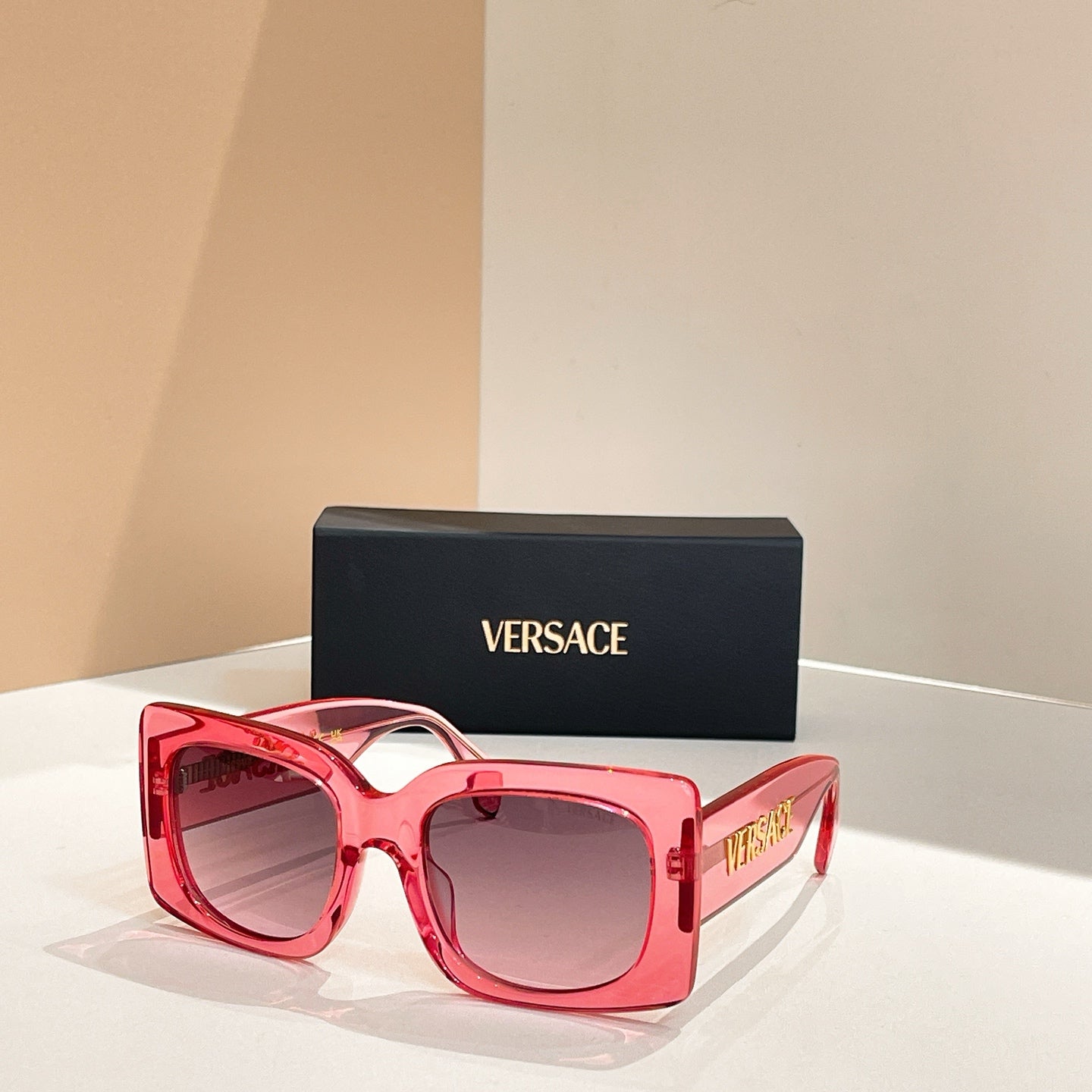 Red-pink oversized square sunglasses with dark lenses and VERSACE logo on temple