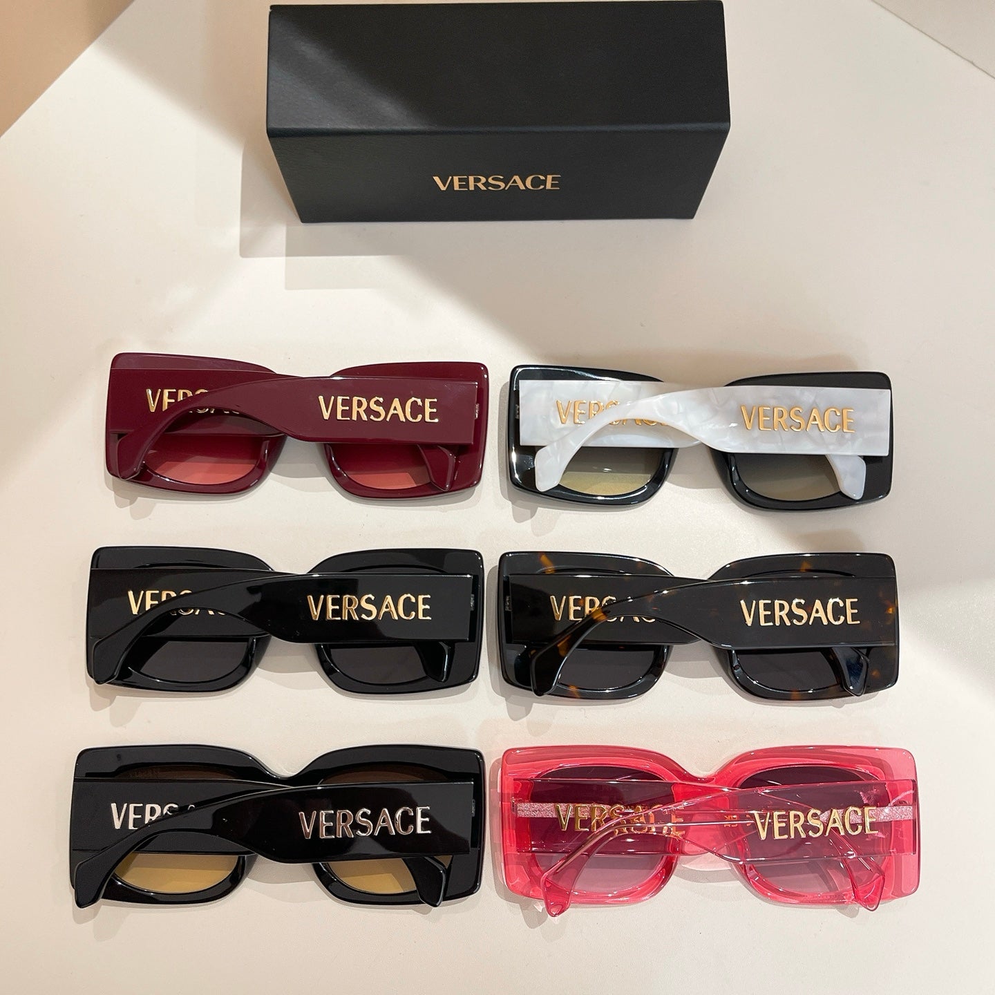 Assorted sunglasses with red, white, black, and transparent frames and VERSACE logos