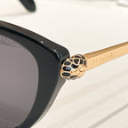 Gold-tone lion head detail on a black round glasses temple
