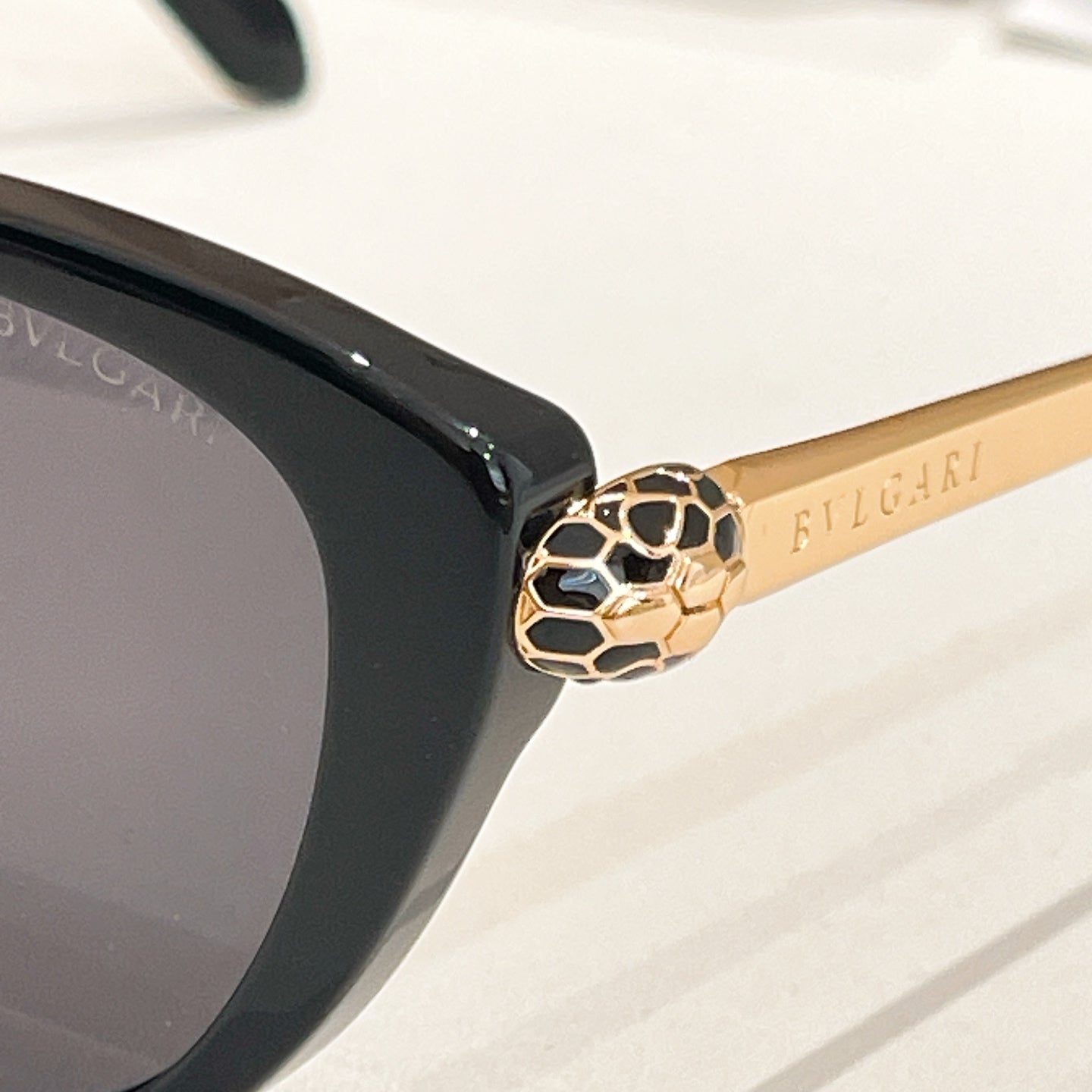 Gold-tone lion head detail on a black round glasses temple