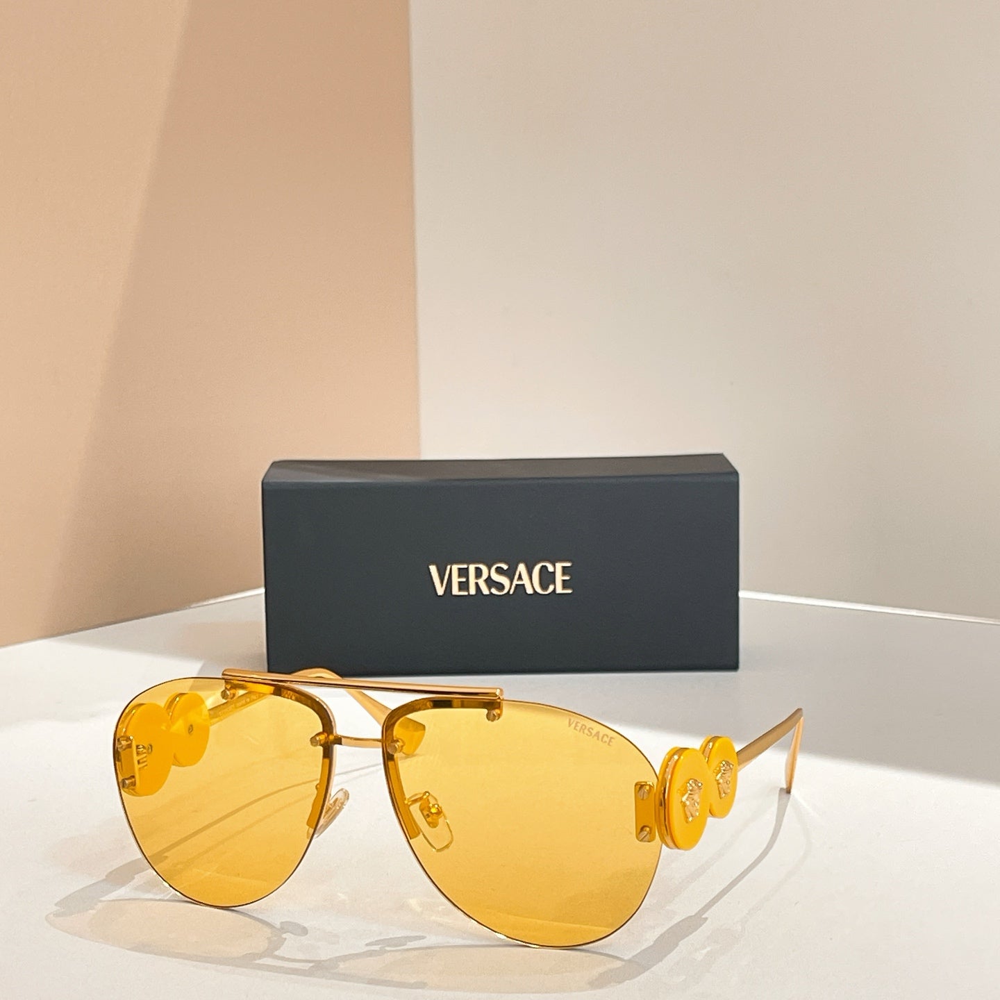 Versace sunglasses with gold frame and bright yellow tinted lenses; logo detail on temples